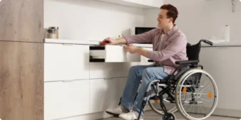 Investing in disability housing: A young man in a wheelchair using an accessible drawer